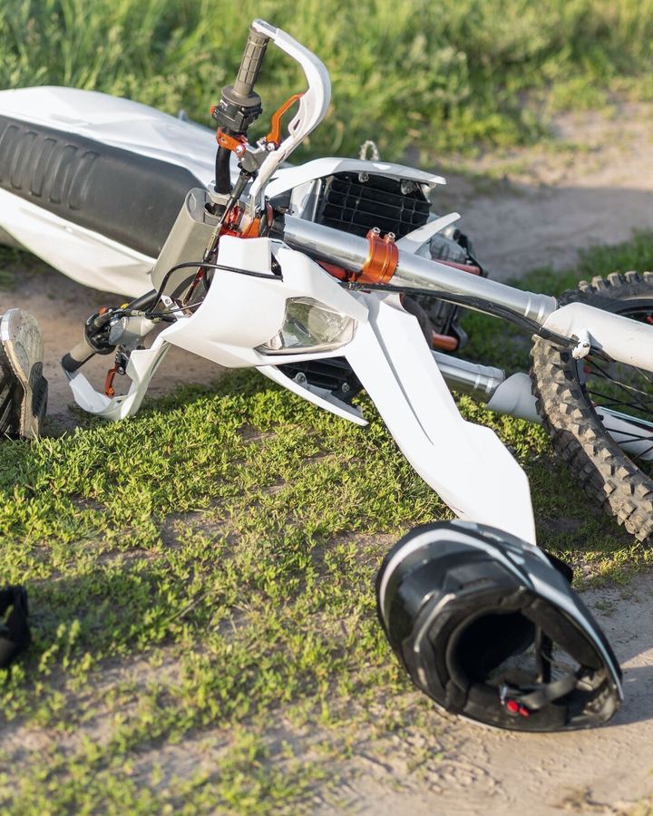 A motorcycle lying on the ground beside a helmet