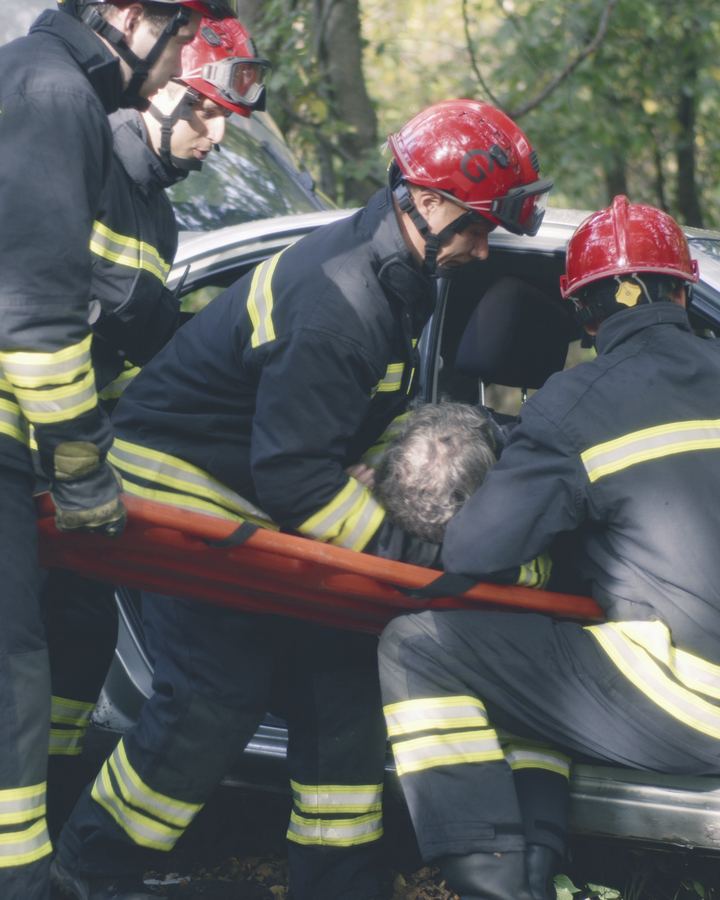 Firefighters helping a person from a car after a crash
